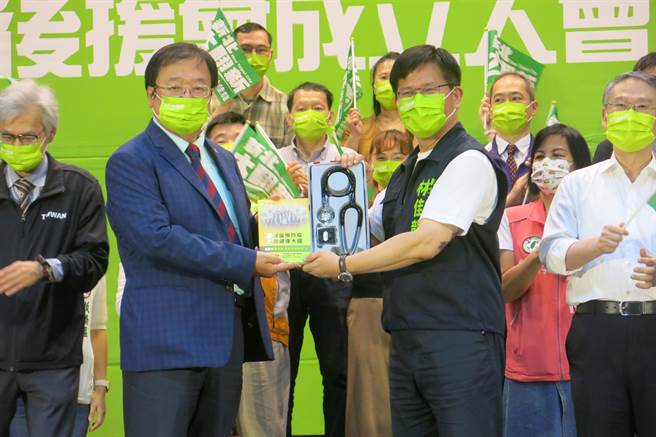 林佳龙从后援会荣誉总会长、民进党立委邱泰源手中接下听诊器和医疗白皮书，象徵「倾听民意、对市政对症下药」。（李奇叡摄）