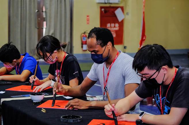 新竹縣首屆縣長盃全國書法決賽，有6名外籍參賽者來自美國非裔的Thomson「唐海澤」（右二），高大身形，低頭書寫，展現書法藝術不受國界、年齡的限制 。（羅浚濱攝）