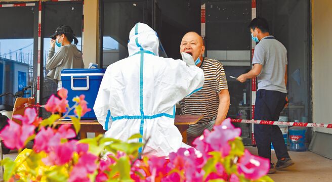 中国疾控中心流行病学首席专家吴尊友23日在微博发文指出，今冬新冠疫情趋势很难判定，以出现全球第六波新冠疫情流行的可能性较大，占一半以上。图为海南省海口江东新区工人排队进行核酸採样。（新华社）