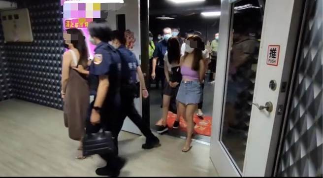 警方将负责人、女服务生及男客带回，由于女子穿着过于火辣，员警还拿条大毛巾先围住。（翻摄照片／高雄洪靖宜传真）