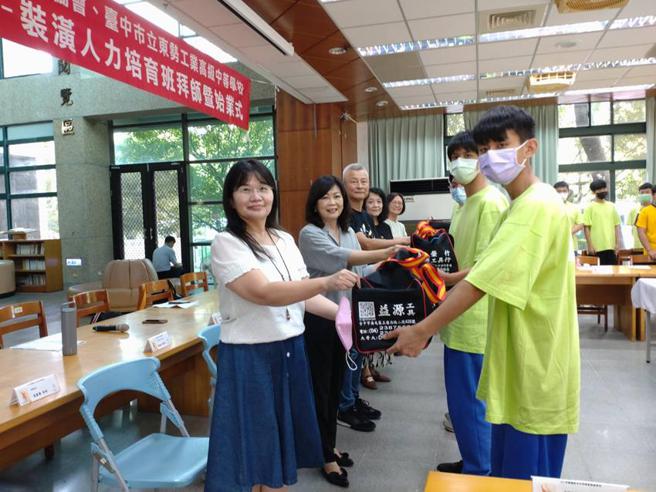 （东势高工28日举行第七届木作班始业式拜师礼，龙宝建设董事长张丽莉(左二)、台湾行动菩萨助学协会理事长陈武华(左三)等人接受学生们奉茶、再送工具袋给学生，象徵技术传承。图／曾丽芳）