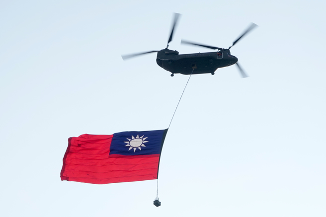 陆航CH-47SD运输直升机，吊挂大幅国旗通过总统府上空。（黄世麒摄）