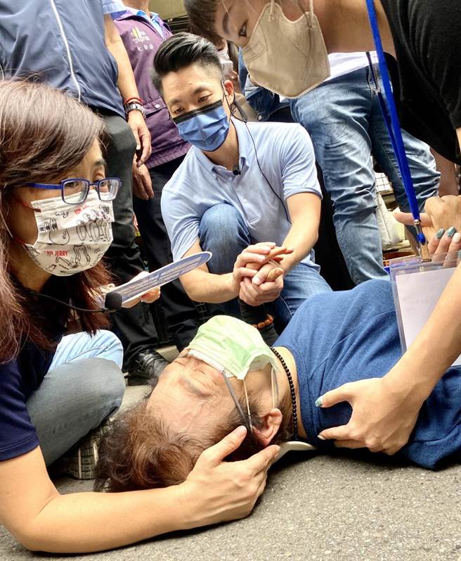 国民党台北市长参选人蒋万安9月初往白兰市场扫街拜票，因市场拥挤，一名妇人摔倒在地，蒋握住妇人手关心慰问，等待救护车。（郭吉铨摄）