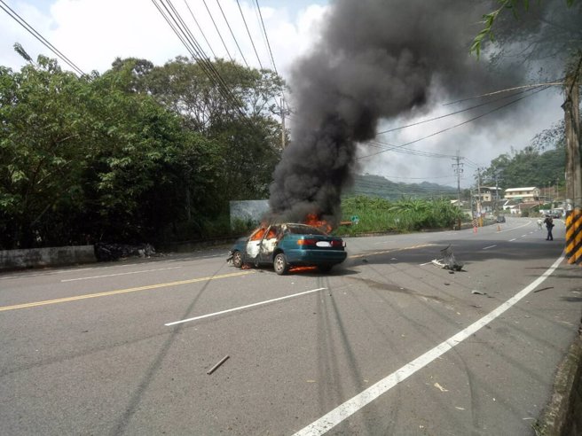 苗栗县狮潭乡台3线122公里路段29日下午发生火烧车事故，一辆轿车自撞山壁后起火燃烧，消防队获报抵达时车辆已全面燃烧，火势伴随浓烟不断窜出，所幸驾驶邱姓女子及时逃生，轻伤送医救治。（图／中央社提供）