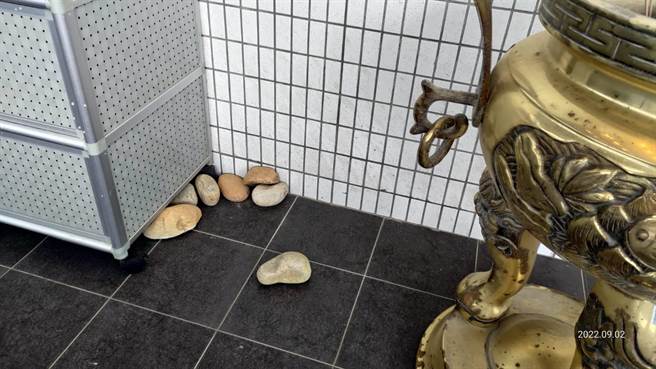 桃园市议员蔡永芳发现八德生命纪念馆大门外有许多石头，一问之下才发现这是民眾为避免风大吹走金纸及供品，只好拿石头来压。（蔡永芳提供／陈梦茹桃园传真）