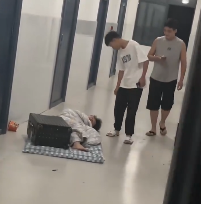 路人发现男子睡在走廊上，好心上前将其拍醒。（翻摄自新浪热点微博）