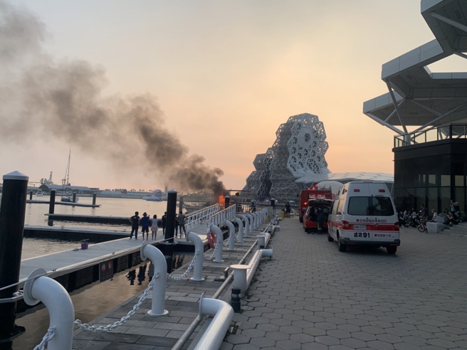 高雄1日下午停泊在光荣码头岸的千万游艇突然冒烟起火，民眾见状立即通报，警消获报后立即到现场扑灭，所幸无人伤亡，至于游艇起火原因仍待消防鑑识人员调查中。（翻摄照片／崔正纲高雄传真）
