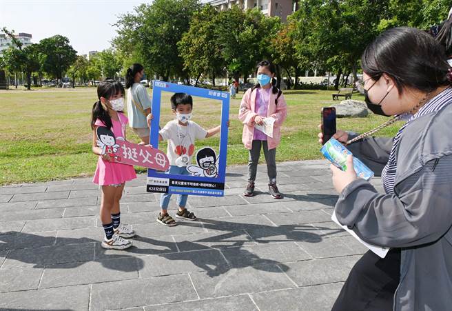 北高雄家扶中心2日在冈山区寿天宫广场举办亲子活动，一名母亲帮孩子拍照。（林瑞益摄）
