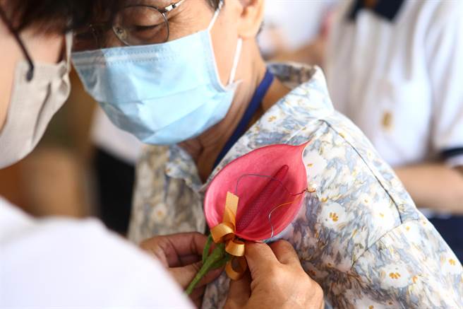 一进场义工们特别为出席的长者别上花朵，送上温暖。（邓博仁摄）