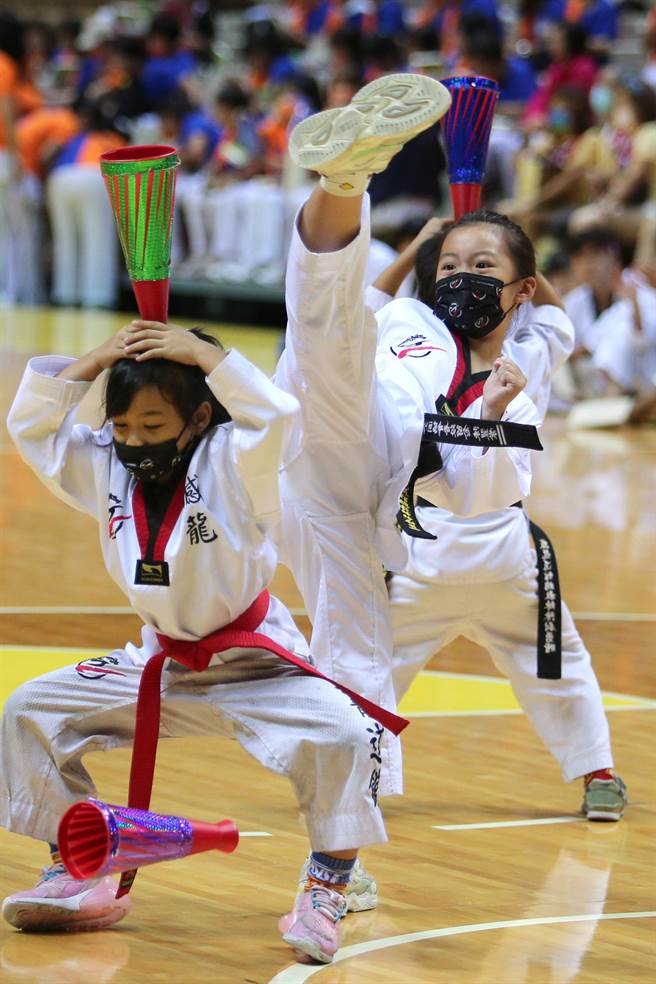 「體育觀摩表演嘉年華」2日在新莊體育館登場，新北市體育總會跆拳道委員會憾龍道館的小朋友，起腳連續踢掉頂在頭上的加油棒，氣勢十足，博得滿堂喝采。（黃世麒攝）