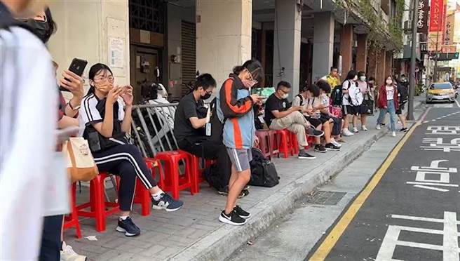 彰化火车站前「学生等候公车」挤在骑楼席地而坐，热心人送红色塑胶椅给学生坐。（民眾提供／吴敏菁彰化传真）
