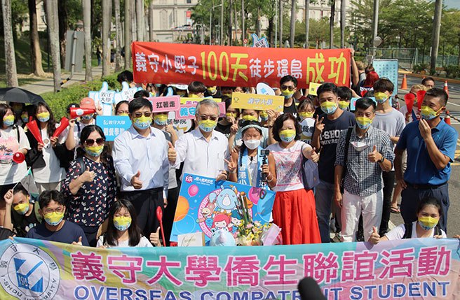 義守大學觀光餐旅學院休閒事業管理學系畢業香港學生梁凱熙，為了在返回香港前深刻體驗台灣，從6月30日起展開徒步環島，今天完成100天的旅程，走回校園，師長、學弟妹與旅程結識的阿姨在校門口列隊歡迎她。(林雅惠攝)