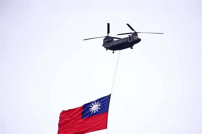  国庆彩排前虽下着大雨，仍有旋翼机吊挂国旗进场，全场观看民眾及贵宾都纷纷起立敬礼，把现场气氛带到最高潮。（邓博仁摄）