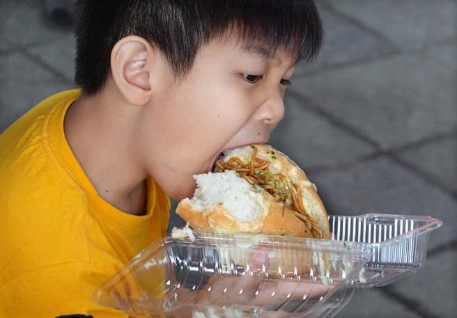 在「商圈嘉年华-台北生活祭」活动中，小朋友大口品尝首次买到的炒麵麵包。（姚志平摄）  