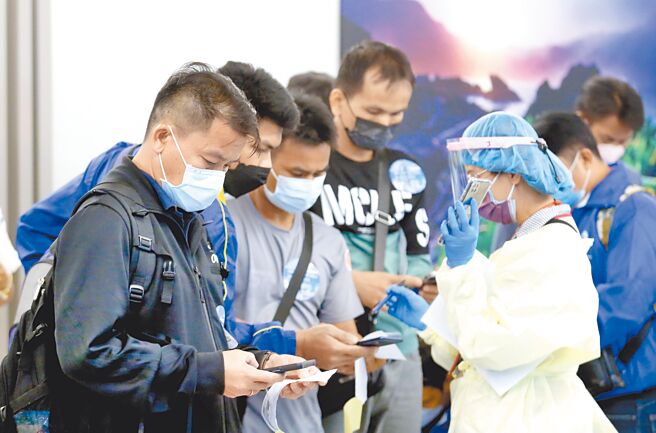 因应13日入境检疫新制，劳动部宣布，产业移工自主防疫期间，只要2日内快筛阴性即可工作。图为桃园机场刚下机的移工填写资料。（范扬光摄）