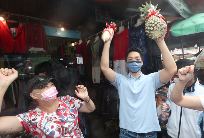 國民黨台北市長參選人蔣萬安（右）9日赴內湖東湖市場掃街拜票，爭取民眾的支持，接過贈送的鳳梨與好彩頭，熱情民眾一同起舞。（鄭任南攝）