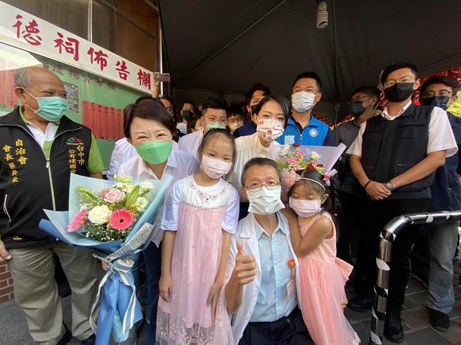 卢秀燕（二排中）陪同高虹安（二排右）考察建国市场，自治会长蔡铃钦接待导览市场摊位，并安排2位小朋友送2人花束、加油打气。（张妍溱摄）