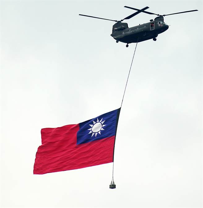 庆祝中华民国111年国庆大会10日在总统府前登场，在唱国歌时，陆军直升机吊挂大国旗飞越总统府前广场。（季志翔摄）
