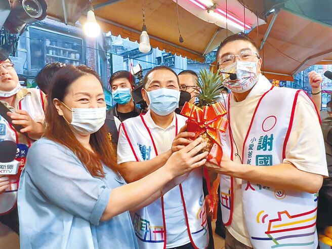 国民党基隆市长参选人谢国梁（前右）9日邀新北市长侯友宜（前中）到基隆，一同前往仁爱市场拜票，摊商送上凤梨高喊「冻蒜」。（陈彩玲摄）