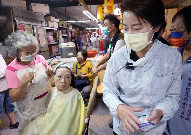 台北市长参选人黄珊珊（右）11日前往木新市场拜票争取支持，1名正在挽面的民眾不满被竞选团队打扰，流露出不悦的神情。（范扬光摄）