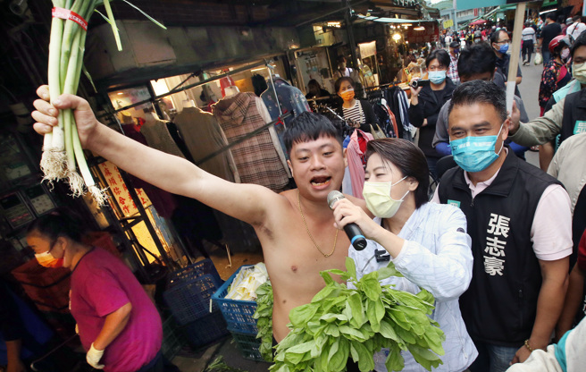 台北市长参选人黄珊珊（中）11日前往木新市场拜票争取支持，1名摊商高举青蒜祝福她高票当选。（范扬光摄）