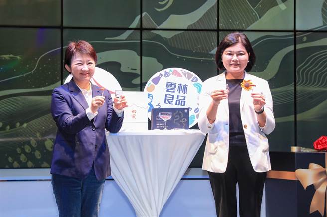 卢秀燕与张丽善2人携手行销，现场1口清酒搭配1口乌鱼子；卢秀燕更说，2项商品不仅包装相搭，滋味也绝佳。（台中市政府提供／潘虹恩台中传真）