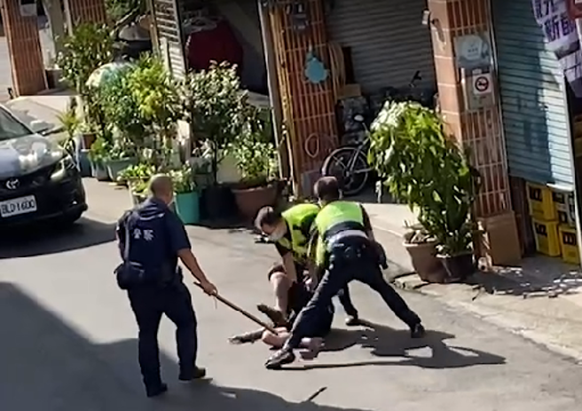 李姓男子双手持菜刀在住家附近路上不断挥舞，警方获报后赶到现场，趁隙将李男手中菜刀击落后，一度在地上扭打，最后顺利压制。(记者爆料网提供)