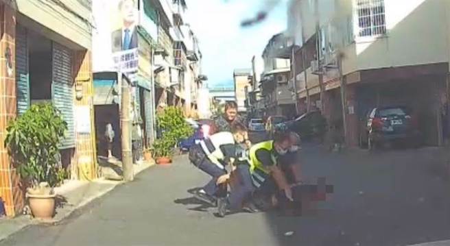 李姓男子双手持菜刀在住家附近路上不断挥舞，警方获报后赶到现场，趁隙将李男手中菜刀击落后，一度在地上扭打，最后顺利压制。(李京生翻摄)