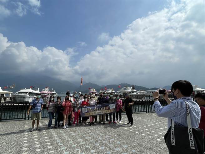 泰国首发团14日抵达日月潭，导游帮旅客在湖畔合影。（杨静茹摄）