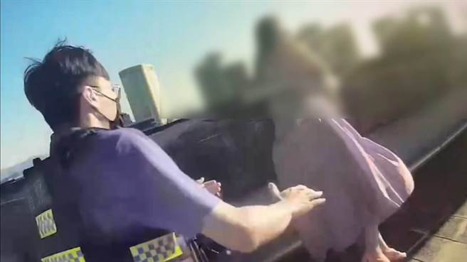 红衣妇人站在顶楼墙边险象环生，在员警耐心劝说下才解除危机。（翻摄照片／林郁平）