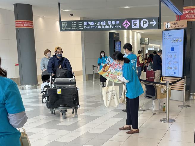 当地人员拉起迎宾布条热情欢迎旅客来到北海道，并赠送小礼物。（何书青摄）