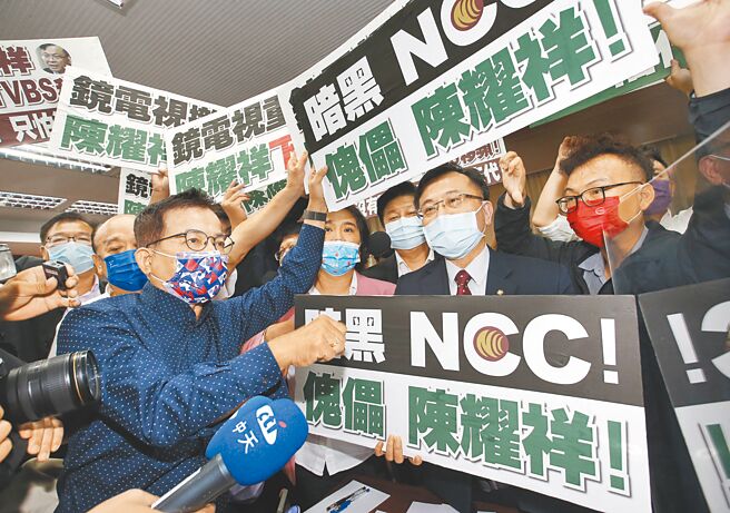镜电视3董1监在上周集体请辞，镜电视董事会形同瓦解，在野党立委呼吁NCC应尽快撤照。图为NCC主委陈耀祥（中右）10月5日在立院备询，遭国民党立委持标语包围。（本报资料照片）