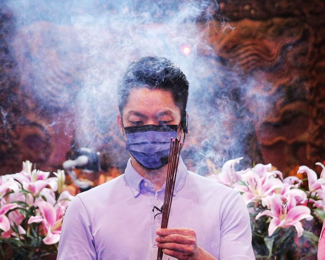 国民党台北市长参选人蒋万安18日走访台北市鱼类批发市场及第一果菜市场，为选战衝刺，争取选民支持。蒋万安在庙宇参拜时，一度被香火烟雾围绕。（黄世麒摄）