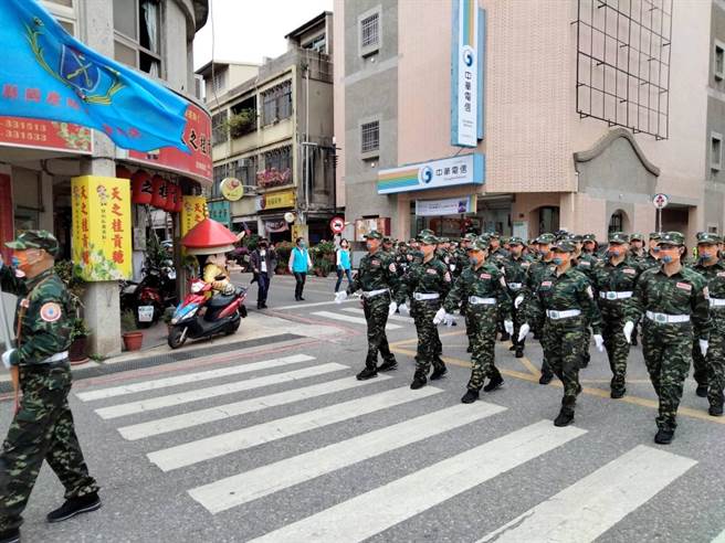60名前金门自卫队的男女队员着迷彩军装、戴军帽，手执国旗，沿路唱军歌答数操演，彷佛回到早期十万大军驻扎时的光荣街景(图／金湖镇公所提供)