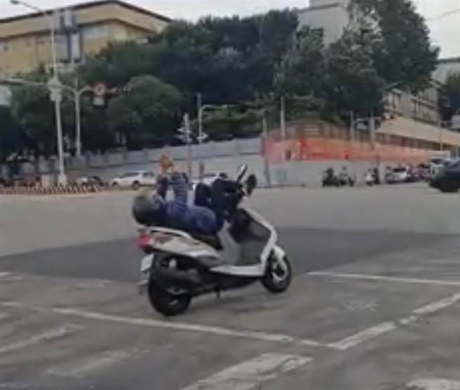 台中市沙鹿区台湾大道与光华路，一名骑士停等红灯时，仰躺机车上打气功，依法已违规可开罚300至600元罚锾。（翻摄脸书「沙鹿之美」）