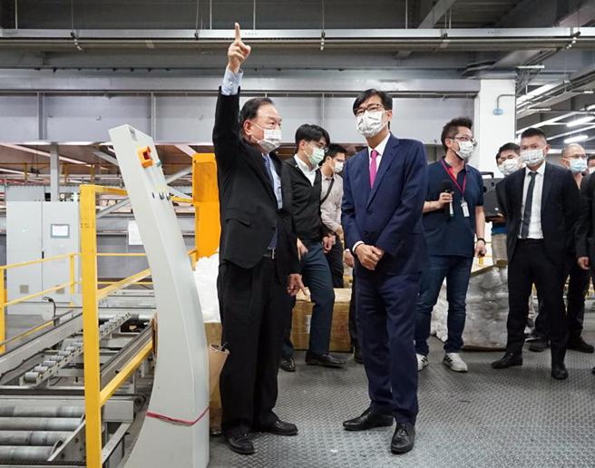 （全联董事长林敏雄(左)20日向高雄市长陈其迈(前右)介绍冈山本洲自动化物流中心运作现况及特色。图／高雄经发局提供）
