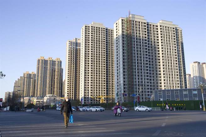 图为山西省太原市，民眾从一在建楼房前经过。（摘自中新社）