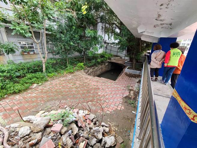 八里国小校园内、司令台旁今年上半年突有塌陷成一大天坑，经过近半年未有修復动作，仅用施工围篱围住。(黄敬文翻摄)