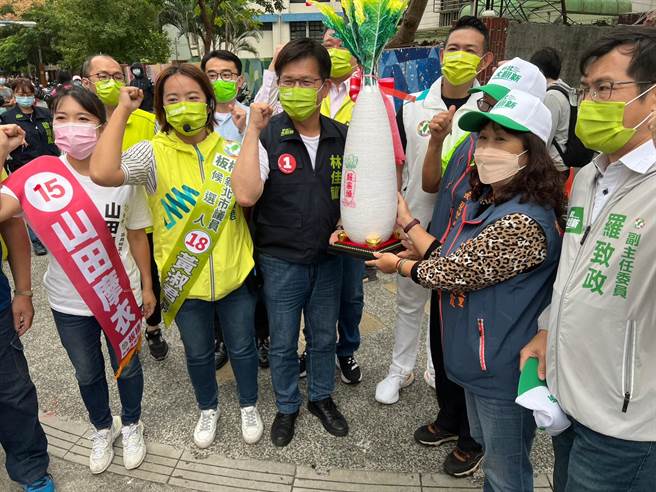 林佳龍下午到板橋重慶黃昏市場掃街拜票，一到場民眾就送上大菜頭。（王揚傑攝）