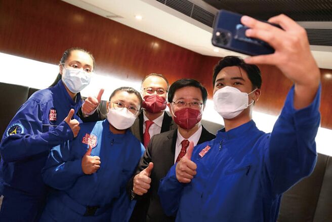 大陆首度在香港澳门招募太空人，条件之一是须具有博士学歷。图为香港特首李家超(右二)10月1日与3名香港太空馆「少年太空人体验营」的前学员合照。（中新社）