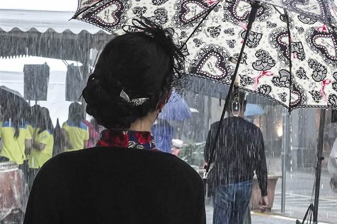 虽然下着大雨，参加大稻埕国际艺术节1920变装活动的女子穿着旗袍，还精心梳妆復古髮型，优雅现身大稻埕街区。（黄子明摄）