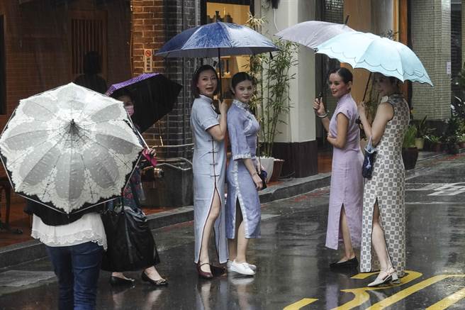 多位女子穿着復古旗袍参加大稻埕国际艺术节1920变装活动，在大雨中撑伞站在街头拍照留念。（黄子明摄）