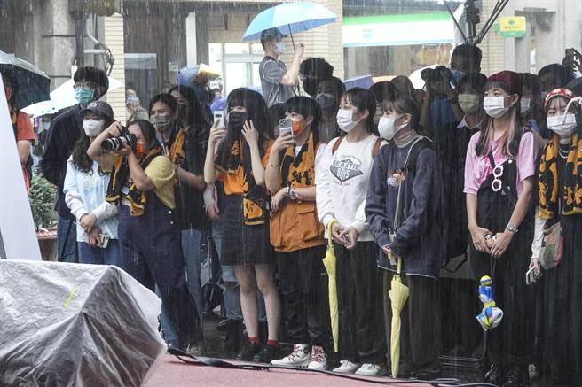 民眾冒雨躲在遮雨棚下观赏大稻埕国际艺术节1920变装活动的各项表演。（黄子明摄）