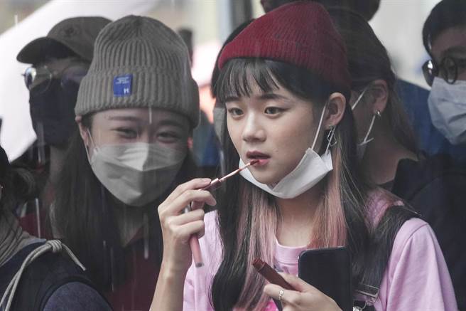 参加大稻埕国际艺术节1920变装活动的年轻女孩在现场擦着口红。（黄子明摄）