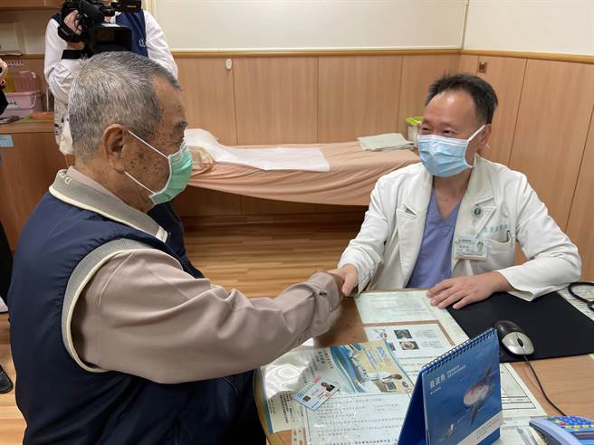 一名老翁手术时受惠于健保制度更新，成为慈济医院此手术的首例健保个案；病人復原状况良好，余荣敏医师握手道恭喜。(台中慈济医院提供／陈世宗台中传真)