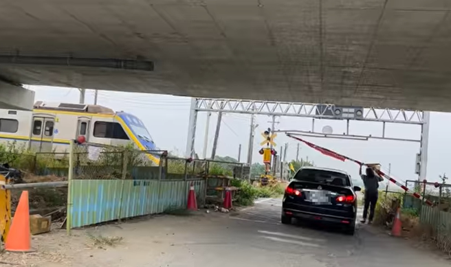 轿车硬闯平交道遭栅栏卡住，妇人协助撑起栅栏。（翻摄自脸书我是柳营人）