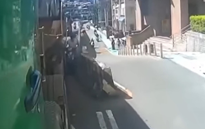 騎士看見前方砂石車旁有縫隙，便騎進去要超車，卻被擠到左右搖晃靠在護欄上。（翻攝自臉書爆料公社）