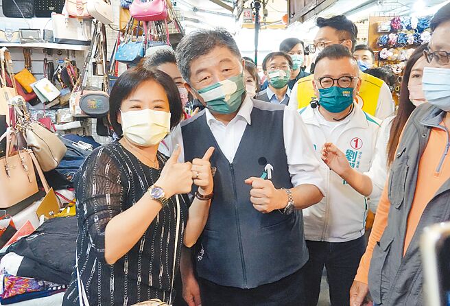 民进党台北市长候选人陈时中（中）25日前往位于台北市武昌街的台湾省城隍庙参香，并到城中市场拜票，与支持者合影留念。（姚志平摄）