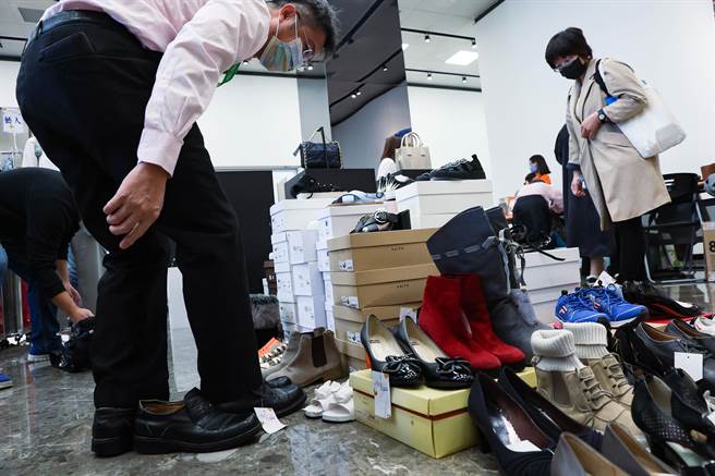 弘道老人福利基金会臺北服务处举办「打『包』爱心『衣』起助老二手精品义卖会」活动，些许民眾趁空檔前来挑选鞋款，并现场试穿。（罗永铭摄）