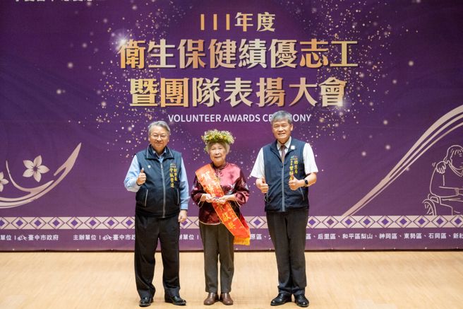 获特殊贡献奖的80岁朱菊兰志工(中)接受臺中市副市长令狐荣达(左)及卫生局长曾梓展(右)亲自表扬，她投身志工服务累计时数超过1万多个小时。(图/臺中市政府卫生局提供)